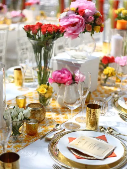 A wider view of the colorful outdoor dining setup. The combination of yellow, pink, and orange flowers creates a joyful atmosphere, perfect for celebrating in the beautiful Mumbai weather.