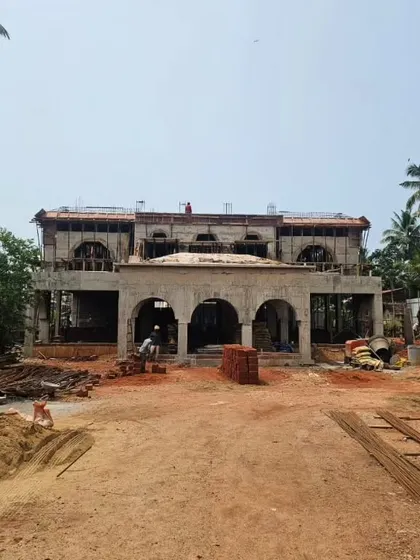 The Veerabhavana Villa in Mangalore during the construction phase. The concrete shell of the building is complete, revealing the grand arches and overall form of the Mediterranean-inspired home before the finishing work began.