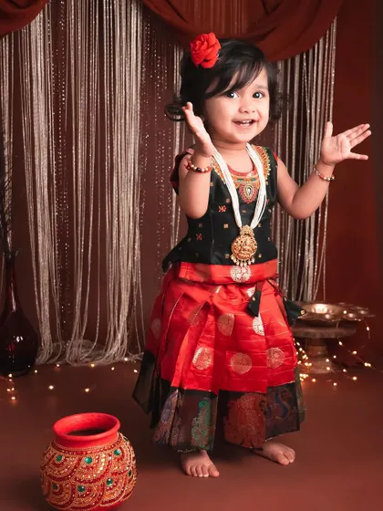 Such a happy and welcoming gesture from this little one. The vibrant colors of her outfit and the surrounding props make this a wonderfully lively photograph.