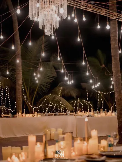 A dreamy sit-down dinner setup under a canopy of lights, with long tables illuminated by hundreds of candles.