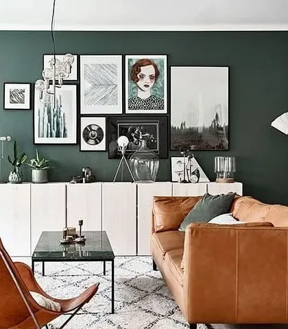A dark green accent wall creates a sophisticated and moody backdrop for this living room. This technique is an effective way to add depth and character to your main living space.