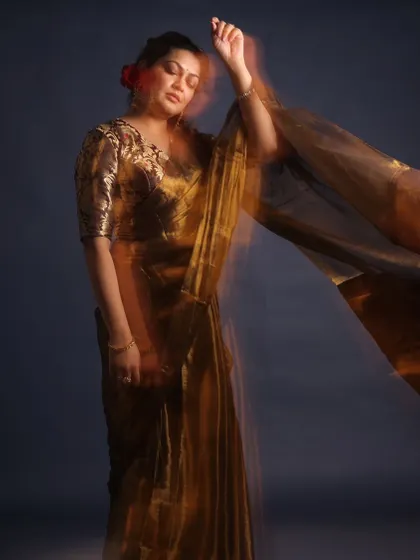 A retro-inspired look for Priyanka Barve. This shimmering gold saree paired with a brocade blouse and red flowers in her hair evokes a timeless, cinematic feel.