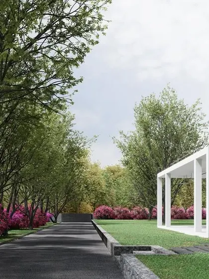 The approach to this weekend retreat is through a driveway lined with mature trees and flowering bushes. The minimalist, glass-walled pavilion appears at the end of the path, creating a sense of arrival at a private and secluded natural oasis.