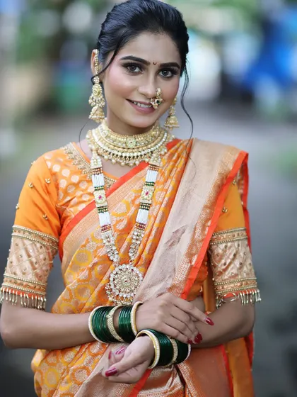 A smiling portrait of the bride, showing how the makeup looks natural and enhances her happiness. The green bangles and traditional jewelry complete the look.