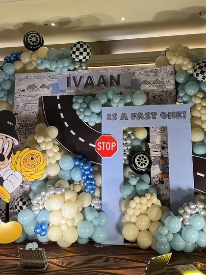 A 'Fast One' birthday with a Mickey the Racer theme. We created a racetrack backdrop with checkered flags, tire details, and a cool blue and yellow color scheme for a little boy who loves cars and Mickey.