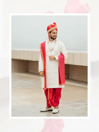 A full-length portrait of the Maharashtrian groom in his traditional attire. The white kurta, red dhoti, and matching stole create a vibrant and classic look.