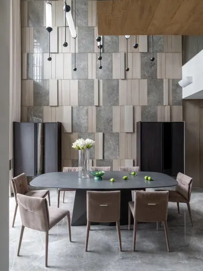 The double-height dining room at the Skyward Residence is all about scale and texture. The wall is clad in a pattern of stone and wood, creating a stunning backdrop for meals and gatherings.