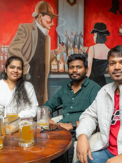 A group enjoying drinks by the Sherlock Holmes mural. The artwork adds to the unique, mystery-themed atmosphere of the pub.