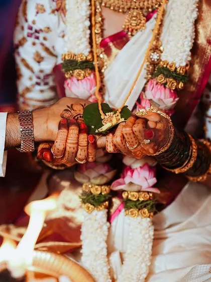 A close-up shot of the couple's hands during a wedding ritual, symbolizing their union and shared journey ahead.