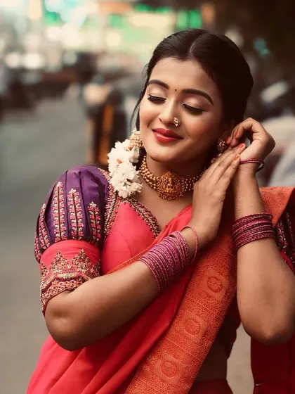 A close-up shot showing the detailed embroidery on the puff sleeves of the blouse, paired with traditional jewelry.