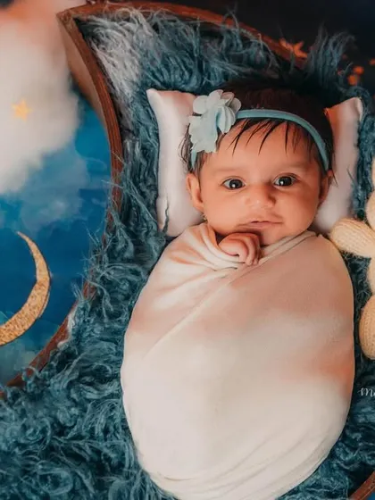 This sweet newborn girl is wide awake and ready for her close-up, nestled in a moon prop with her bunny friend.