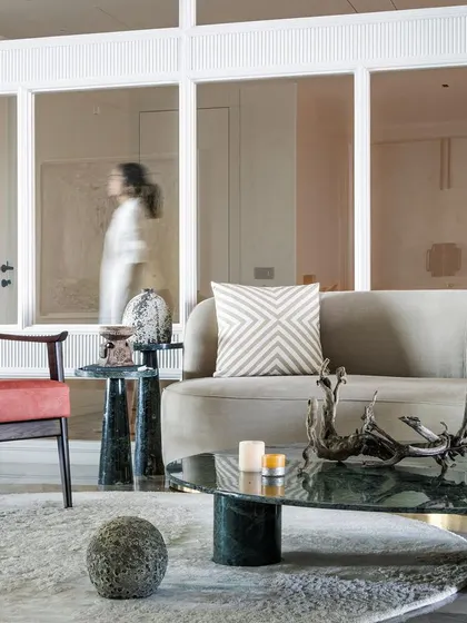Deep, muted red chairs make a statement while adding warmth, perfectly balanced by the rich green marble coffee table. The pale green rug creates a soft, calming foundation that lets the bold pieces shine.