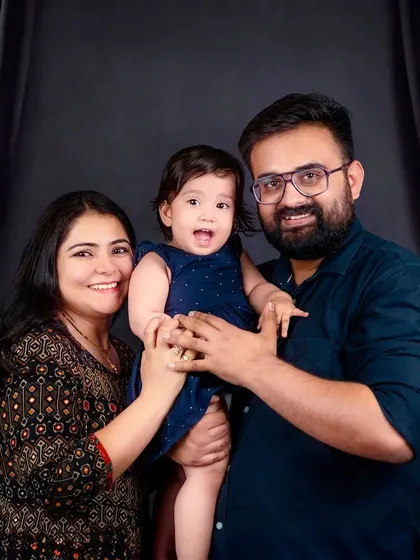A beautiful family portrait against a dark, elegant curtain backdrop. The family's smiles and close embrace create a feeling of warmth and unity.