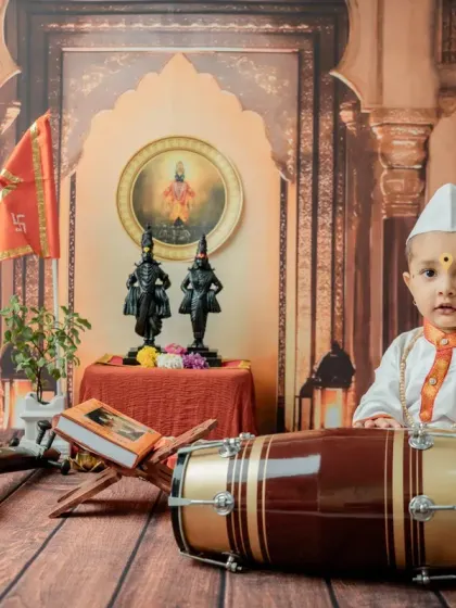 A direct, engaging portrait of the baby looking at the camera while seated with the drum.