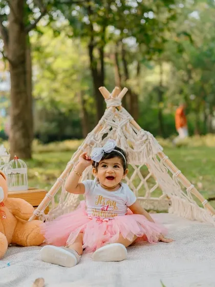 Waving hello to being one! This joyful shot from an outdoor first birthday session captures the birthday girl's happy spirit.