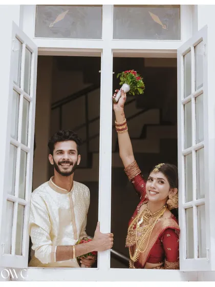 A celebratory moment with the bride and groom looking out a window, capturing the joy of their wedding day.