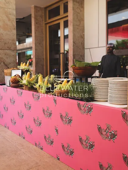 A food counter is wrapped in a vibrant pink fabric printed with Gond art motifs.