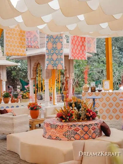 A central seating area under a canopy of scalloped drapes and hanging fabrics, with a custom-printed ottoman as the centerpiece.