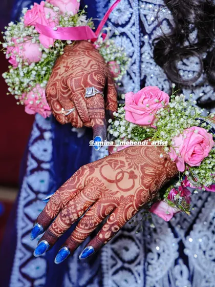 A beautiful shot of a mature henna stain, accessorized with floral bracelets for a festive occasion. The dark henna complements the bright flowers perfectly.