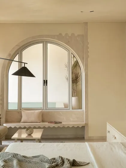 A cozy seating nook in the master suite, set within an arched bay window that offers languid views of the pool.