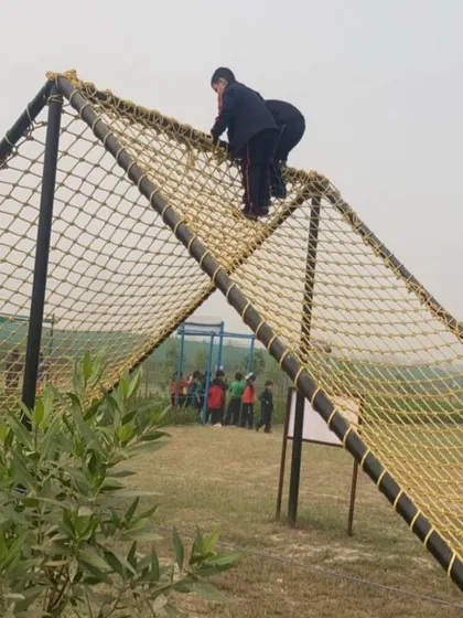 Students work together to conquer the commando net climb. This challenging activity builds physical strength, coordination, and the spirit of perseverance.