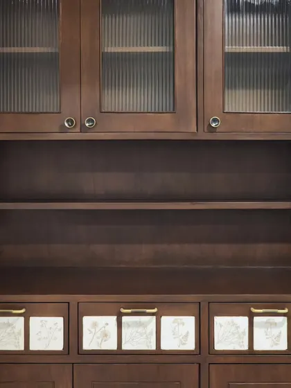 A crockery unit featuring fluted glass doors and custom-made ceramic tile inlays on the drawers. This piece combines traditional craft with modern design, providing both functional storage and a beautiful focal point.