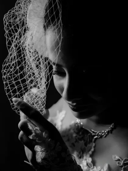 Another angle of the bride with her birdcage veil, in a moody black and white style. This close-up highlights her expression and the texture of the veil.