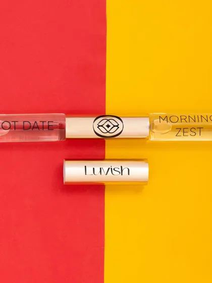 A bold and graphic flatlay for a dual ended perfume roller. The split color background of red and yellow creates a high contrast, modern look that grabs attention.