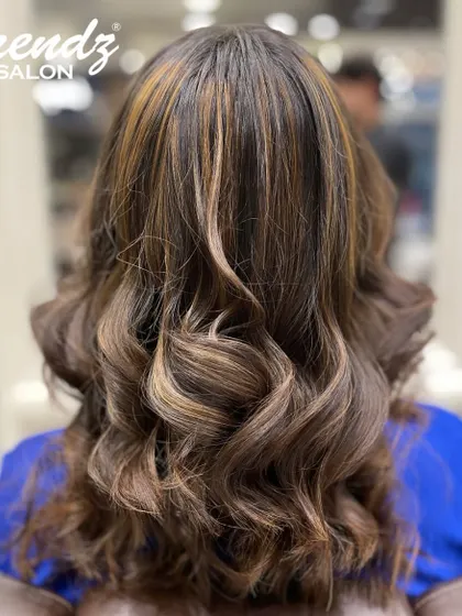 A beautiful example of our balayage work, with perfectly blended highlights on a dark base, styled into glamorous curls.