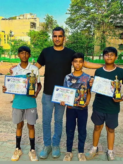 A coach stands proudly with champions Ansh, Satish, and Naman. The bond between coach and player is key to building the confidence needed to win.