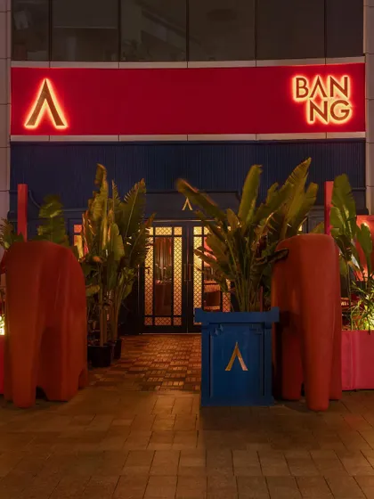 The vibrant, theatrical entrance to BANNG in Gurgaon. The design uses a bold palette of red and blue, along with playful elephant sculptures, to signal a fusion of Thai and Indian cultural narratives.