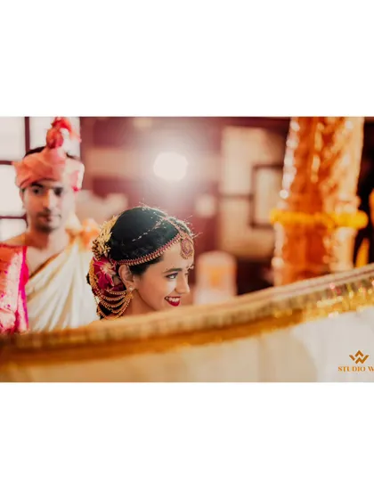 The bride's joyful expression as she peeks over the Antarpat, the cloth that separates the couple before they see each other.