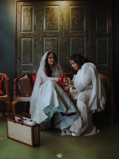 A quiet moment between two women in traditional Muslim attire, sharing a conversation on a bench.