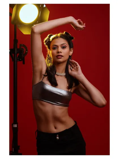 A dynamic studio shot with dramatic lighting. The model's pose and the red background create a high-energy, eye-catching fashion photograph.