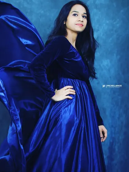 This royal blue velvet and satin gown is a classic choice for pre-wedding shoots or formal events. The flowing trail adds a touch of drama.