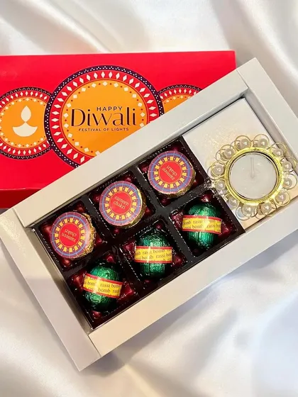 This compact Diwali gift box contains an assortment of cracker-themed chocolates and a pearl-accented diya. It's a charming and festive option for bulk corporate orders.