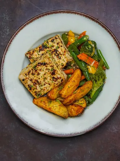 A close-up of a grilled paneer platter, showcasing the seasoning and char marks, served with roasted vegetables.