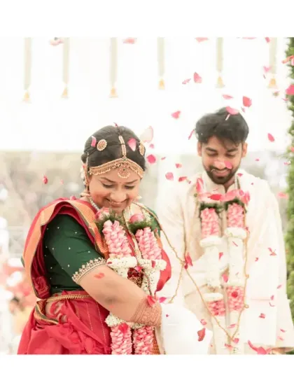 A shower of pink petals rains down on the couple during their South Indian wedding ceremony. The soft colours and their happy expressions create a dreamy and romantic atmosphere.