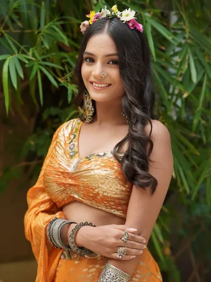 A boho chic Haldi look. The minimal makeup, loose curls, and fresh flower crown create a look that is both traditional and modern.