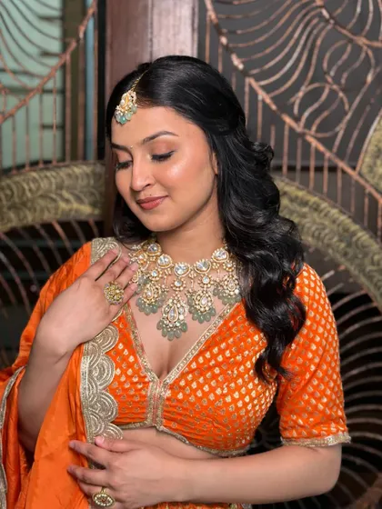 A portrait showcasing the minimal yet impactful glam of this orange lehenga look.