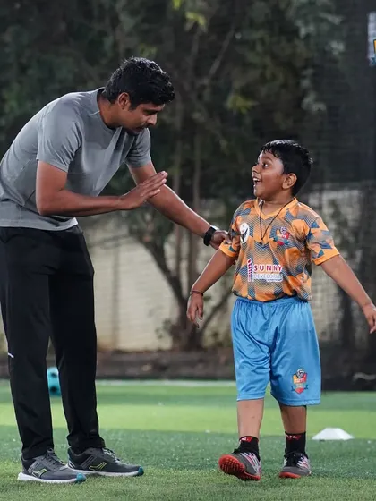 A coach shares a light-hearted moment with a young player, showing that training can be fun and motivational.