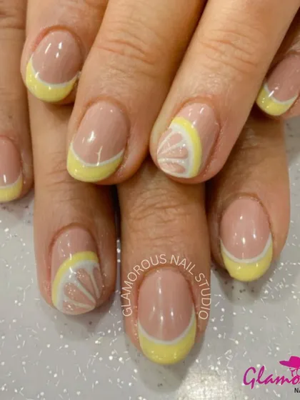 Squeeze the day with these zesty lemon-inspired nails. This design features a yellow French tip with an accent nail showing a detailed, hand-painted lemon slice.