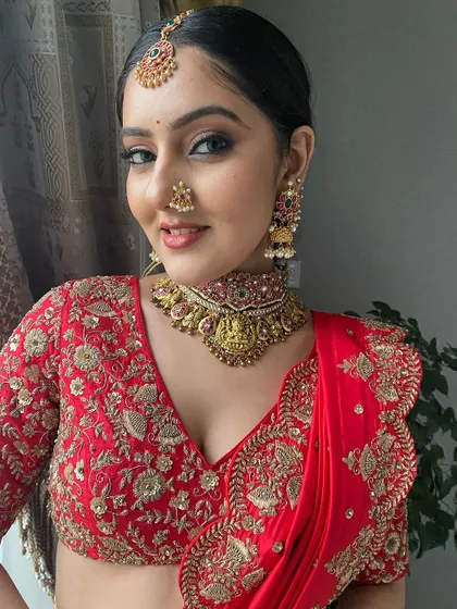 A classic South Indian look with a red saree, temple jewelry, and a traditional nose ring. The makeup is timeless, with a winged liner and radiant skin.