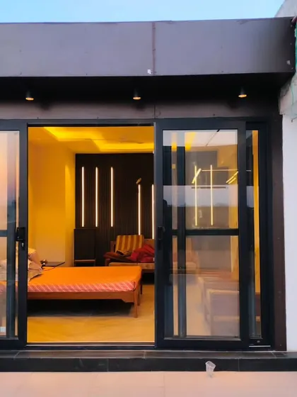 The exterior of a completed terrace room in Palam Vihar, Gurgaon, with modern black-framed sliding glass doors.