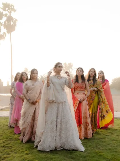 A beautiful portrait of the bride with her bridesmaids, all standing together in a field during golden hour.
