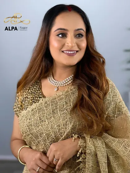 A smiling portrait in a golden saree. The makeup is soft and glowing, perfect for an elegant evening event.