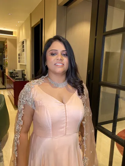 A close-up portrait showing her radiant smile. The makeup is polished and sophisticated, perfect for hosting a special event.