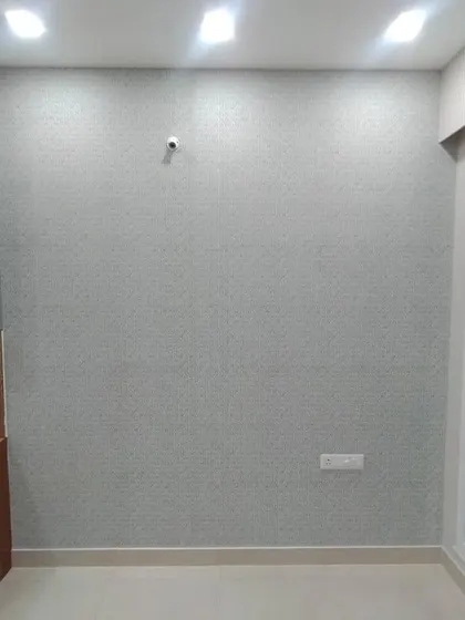 A simple, light-colored textured wallpaper on a clean, empty wall.