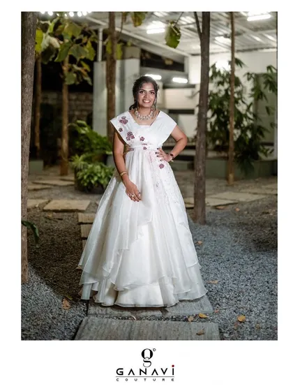 A client looking effortlessly gorgeous in an airy white embroidered organza gown. The layered skirt and delicate floral embroidery on the shoulder add a touch of romance.