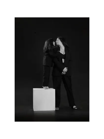 A daughter's sweet kiss for her mother. The dramatic lighting and black and white treatment give this tender moment a timeless, cinematic quality.